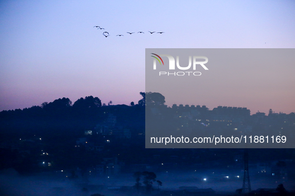 The sun rises behind the hills surrounding Kathmandu Valley as the cold fog covers the bowl-shaped valley in Kathmandu, Nepal, on December 1...