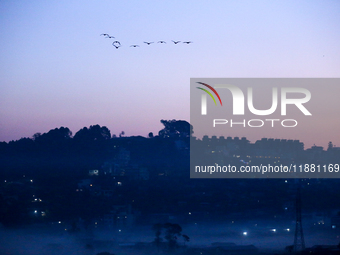 The sun rises behind the hills surrounding Kathmandu Valley as the cold fog covers the bowl-shaped valley in Kathmandu, Nepal, on December 1...