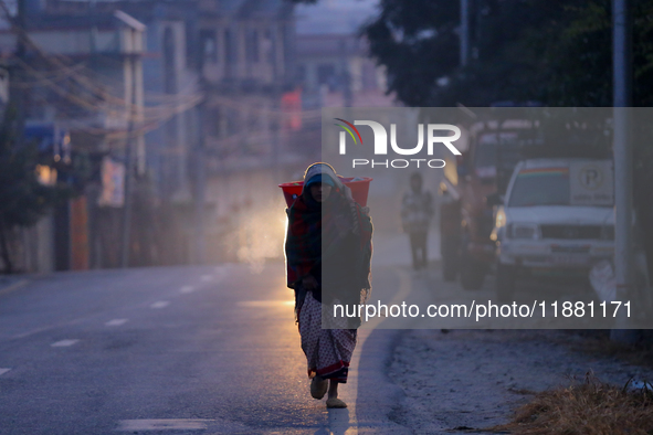 A Nepali woman carries sticks to make a bonfire as the temperature drops in Kathmandu, Nepal, on December 19, 2024, with the onset of winter...