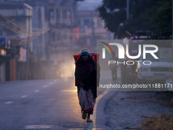 A Nepali woman carries sticks to make a bonfire as the temperature drops in Kathmandu, Nepal, on December 19, 2024, with the onset of winter...