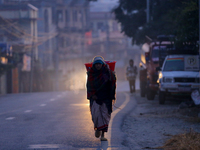 A Nepali woman carries sticks to make a bonfire as the temperature drops in Kathmandu, Nepal, on December 19, 2024, with the onset of winter...