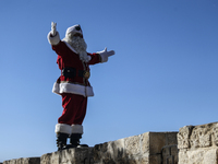 In Jerusalem, Israel, on December 19, 2024, Christian Palestinian Issa Kassissieh, dressed as Santa Claus, greets the public from the old ci...