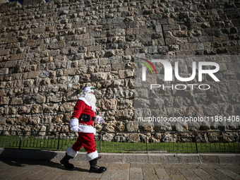 In Jerusalem, Israel, on December 19, 2024, Christian Palestinian Issa Kassissieh, dressed as Santa Claus, greets the public from the old ci...