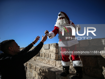 In Jerusalem, Israel, on December 19, 2024, Christian Palestinian Issa Kassissieh, dressed as Santa Claus, greets the public from the old ci...