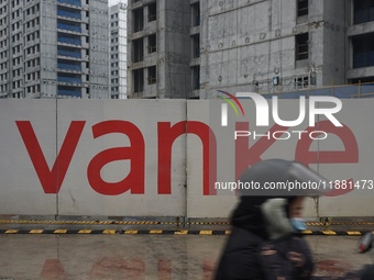 A pedestrian passes a newly built commercial housing complex of China Vanke in Hangzhou, Zhejiang province, China, on December 19, 2024. (