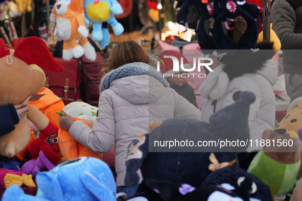 A colorful display of plush toys is at a market in Grafing, Bavaria, Germany, on December 15, 2024. Children browse the market atmosphere. 