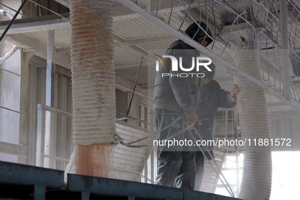 Workers fill a container with grain at a grain elevator in Chernihiv region, Ukraine, on December 18, 2024. 