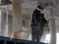 Workers fill a container with grain at a grain elevator in Chernihiv region, Ukraine, on December 18, 2024. (