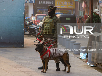 An Indian security personnel, along with a sniffer dog, guards a road in Srinagar, Jammu and Kashmir, on December 19, 2024. Indian security...