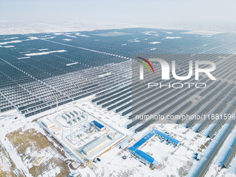 Operation and maintenance personnel clean snow on photovoltaic modules in the 100,000-kilowatt photovoltaic power generation project area of...