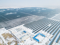 Operation and maintenance personnel clean snow on photovoltaic modules in the 100,000-kilowatt photovoltaic power generation project area of...