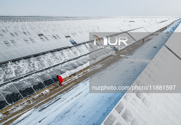 Operation and maintenance personnel clean snow on photovoltaic modules in the 100,000-kilowatt photovoltaic power generation project area of...