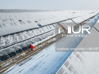 Operation and maintenance personnel clean snow on photovoltaic modules in the 100,000-kilowatt photovoltaic power generation project area of...