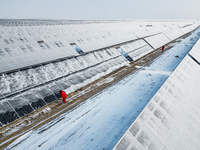 Operation and maintenance personnel clean snow on photovoltaic modules in the 100,000-kilowatt photovoltaic power generation project area of...