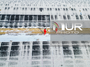 Operation and maintenance personnel clean snow on photovoltaic modules in the 100,000-kilowatt photovoltaic power generation project area of...