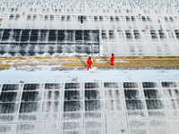 Operation and maintenance personnel clean snow on photovoltaic modules in the 100,000-kilowatt photovoltaic power generation project area of...