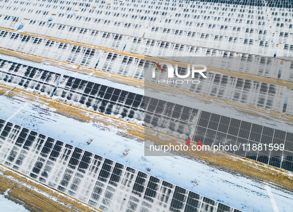 Operation and maintenance personnel clean snow on photovoltaic modules in the 100,000-kilowatt photovoltaic power generation project area of...