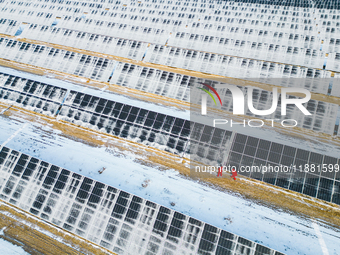 Operation and maintenance personnel clean snow on photovoltaic modules in the 100,000-kilowatt photovoltaic power generation project area of...