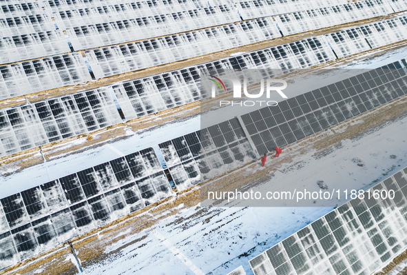 Operation and maintenance personnel clean snow on photovoltaic modules in the 100,000-kilowatt photovoltaic power generation project area of...