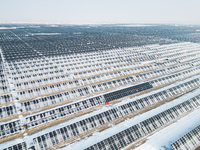 Operation and maintenance personnel clean snow on photovoltaic modules in the 100,000-kilowatt photovoltaic power generation project area of...