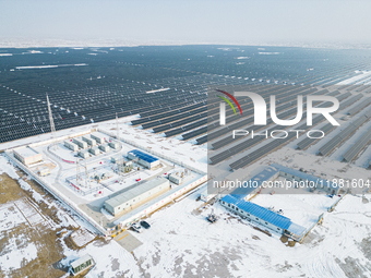 Operation and maintenance personnel clean snow on photovoltaic modules in the 100,000-kilowatt photovoltaic power generation project area of...