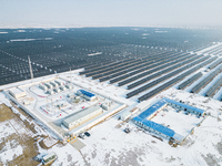 Operation and maintenance personnel clean snow on photovoltaic modules in the 100,000-kilowatt photovoltaic power generation project area of...