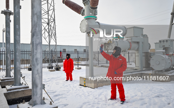 Operation and maintenance personnel clean snow on photovoltaic modules in the 100,000-kilowatt photovoltaic power generation project area of...