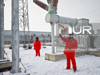 Operation and maintenance personnel clean snow on photovoltaic modules in the 100,000-kilowatt photovoltaic power generation project area of...