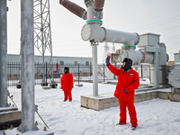 Operation and maintenance personnel clean snow on photovoltaic modules in the 100,000-kilowatt photovoltaic power generation project area of...