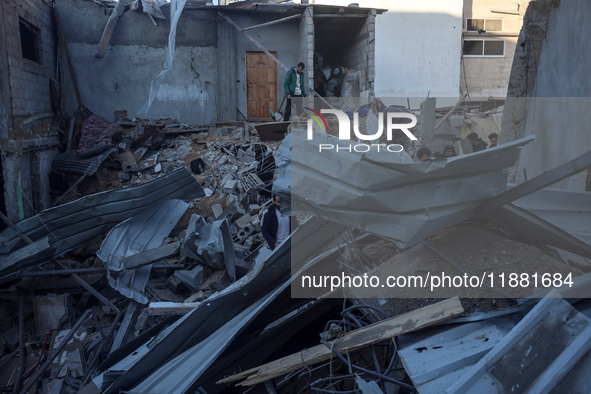 Palestinians inspect the site of an Israeli airstrike on a house amid the ongoing conflict between Israel and Hamas in Al-Maghazi, central G...