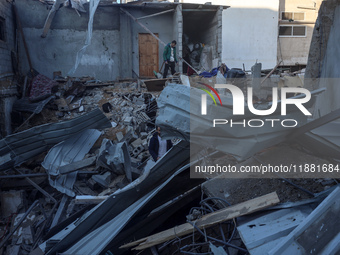 Palestinians inspect the site of an Israeli airstrike on a house amid the ongoing conflict between Israel and Hamas in Al-Maghazi, central G...