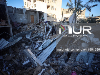 Palestinians inspect the site of an Israeli airstrike on a house amid the ongoing conflict between Israel and Hamas in Al-Maghazi, central G...