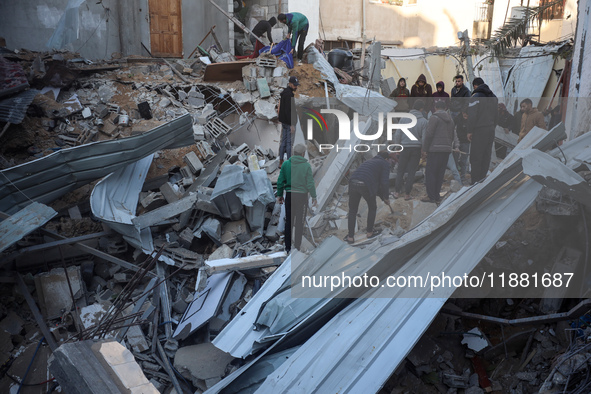 Palestinians inspect the site of an Israeli airstrike on a house amid the ongoing conflict between Israel and Hamas in Al-Maghazi, central G...