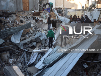 Palestinians inspect the site of an Israeli airstrike on a house amid the ongoing conflict between Israel and Hamas in Al-Maghazi, central G...