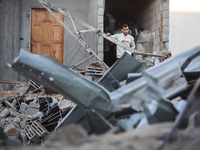 Palestinians inspect the site of an Israeli airstrike on a house amid the ongoing conflict between Israel and Hamas in Al-Maghazi, central G...