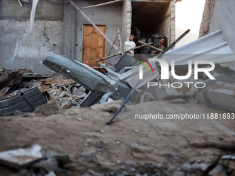 Palestinians inspect the site of an Israeli airstrike on a house amid the ongoing conflict between Israel and Hamas in Al-Maghazi, central G...