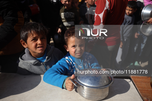 Palestinians gather to receive food cooked by a charity kitchen amid a hunger crisis as the Israel-Gaza conflict continues in Deir el-Balah,...