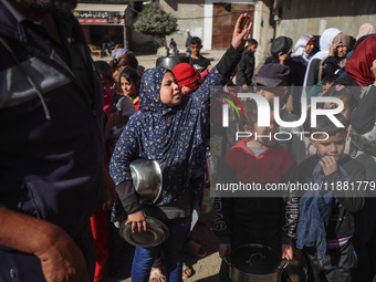 Palestinians gather to receive food cooked by a charity kitchen amid a hunger crisis as the Israel-Gaza conflict continues in Deir el-Balah,...