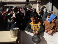 Palestinians gather to receive food cooked by a charity kitchen amid a hunger crisis as the Israel-Gaza conflict continues in Deir el-Balah,...