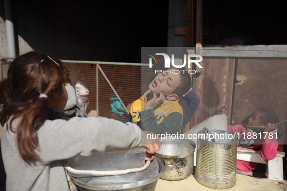 Palestinians gather to receive food cooked by a charity kitchen amid a hunger crisis as the Israel-Gaza conflict continues in Deir el-Balah,...