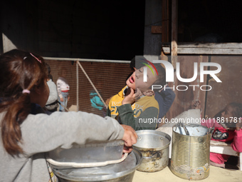 Palestinians gather to receive food cooked by a charity kitchen amid a hunger crisis as the Israel-Gaza conflict continues in Deir el-Balah,...