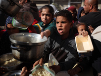 Palestinians gather to receive food cooked by a charity kitchen amid a hunger crisis as the Israel-Gaza conflict continues in Deir el-Balah,...