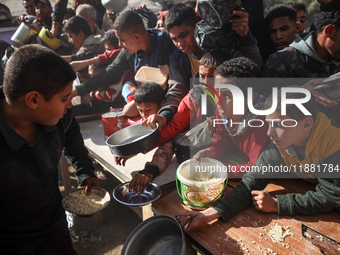 Palestinians gather to receive food cooked by a charity kitchen amid a hunger crisis as the Israel-Gaza conflict continues in Deir el-Balah,...