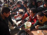 Palestinians gather to receive food cooked by a charity kitchen amid a hunger crisis as the Israel-Gaza conflict continues in Deir el-Balah,...