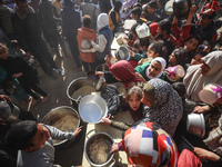 Palestinians gather to receive food cooked by a charity kitchen amid a hunger crisis as the Israel-Gaza conflict continues in Deir el-Balah,...