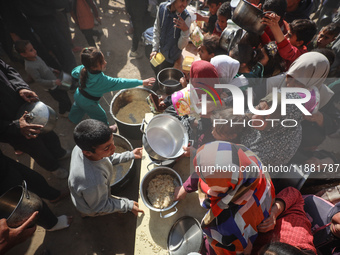 Palestinians gather to receive food cooked by a charity kitchen amid a hunger crisis as the Israel-Gaza conflict continues in Deir el-Balah,...