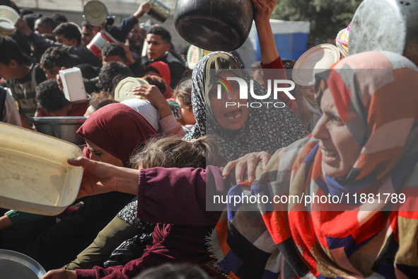 Palestinians gather to receive food cooked by a charity kitchen amid a hunger crisis as the Israel-Gaza conflict continues in Deir el-Balah,...