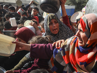 Palestinians gather to receive food cooked by a charity kitchen amid a hunger crisis as the Israel-Gaza conflict continues in Deir el-Balah,...