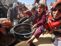 Palestinians gather to receive food cooked by a charity kitchen amid a hunger crisis as the Israel-Gaza conflict continues in Deir el-Balah,...