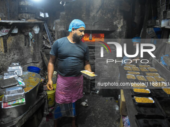 Workers make traditional fruit cake in a wood fire oven at a 100-year-old bakery ahead of Christmas celebrations in Kolkata, India, on Decem...